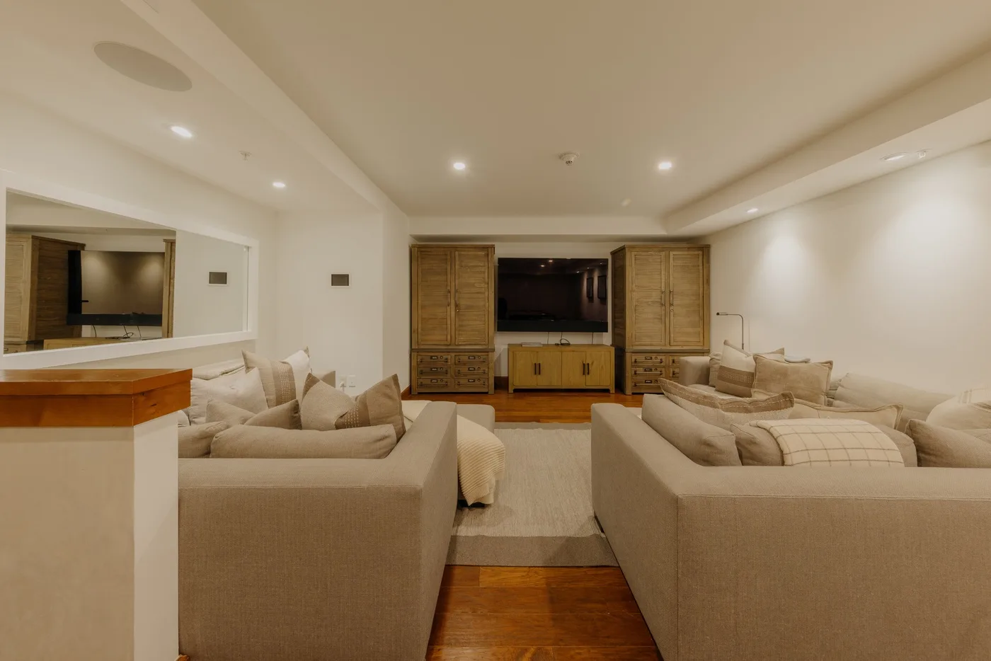 A living room with seating arranged around a television and wooden cabinetry.