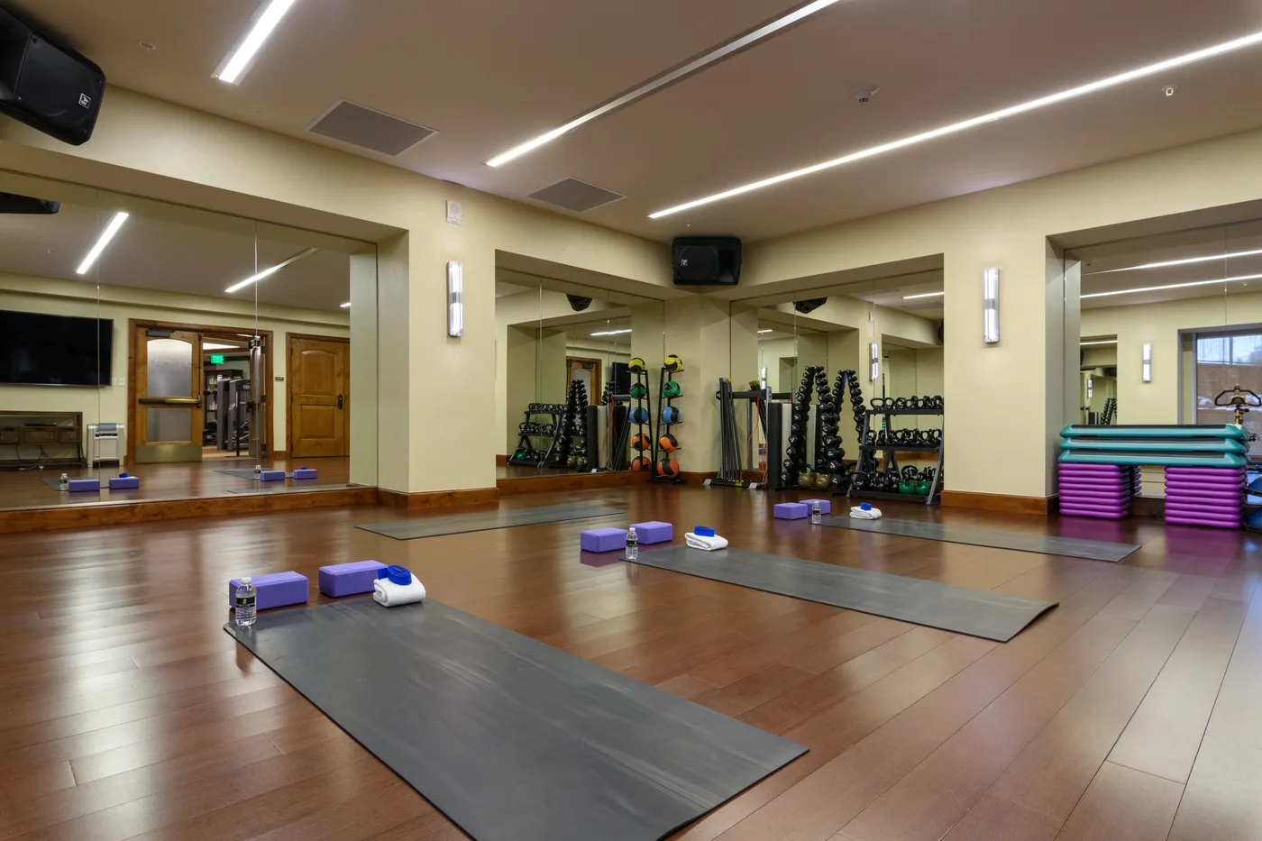 A mirrored exercise studio with floor mats and fitness equipment.
