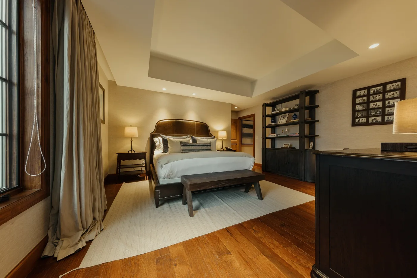 A bedroom with a bed, bedside lamps, and a large area rug.