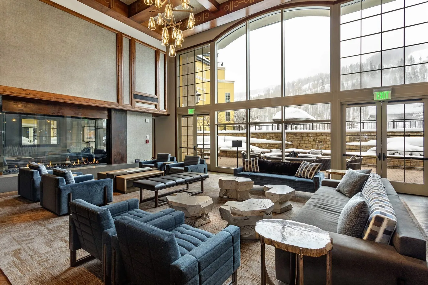 A spacious lounge with seating arranged around low tables beside large windows.