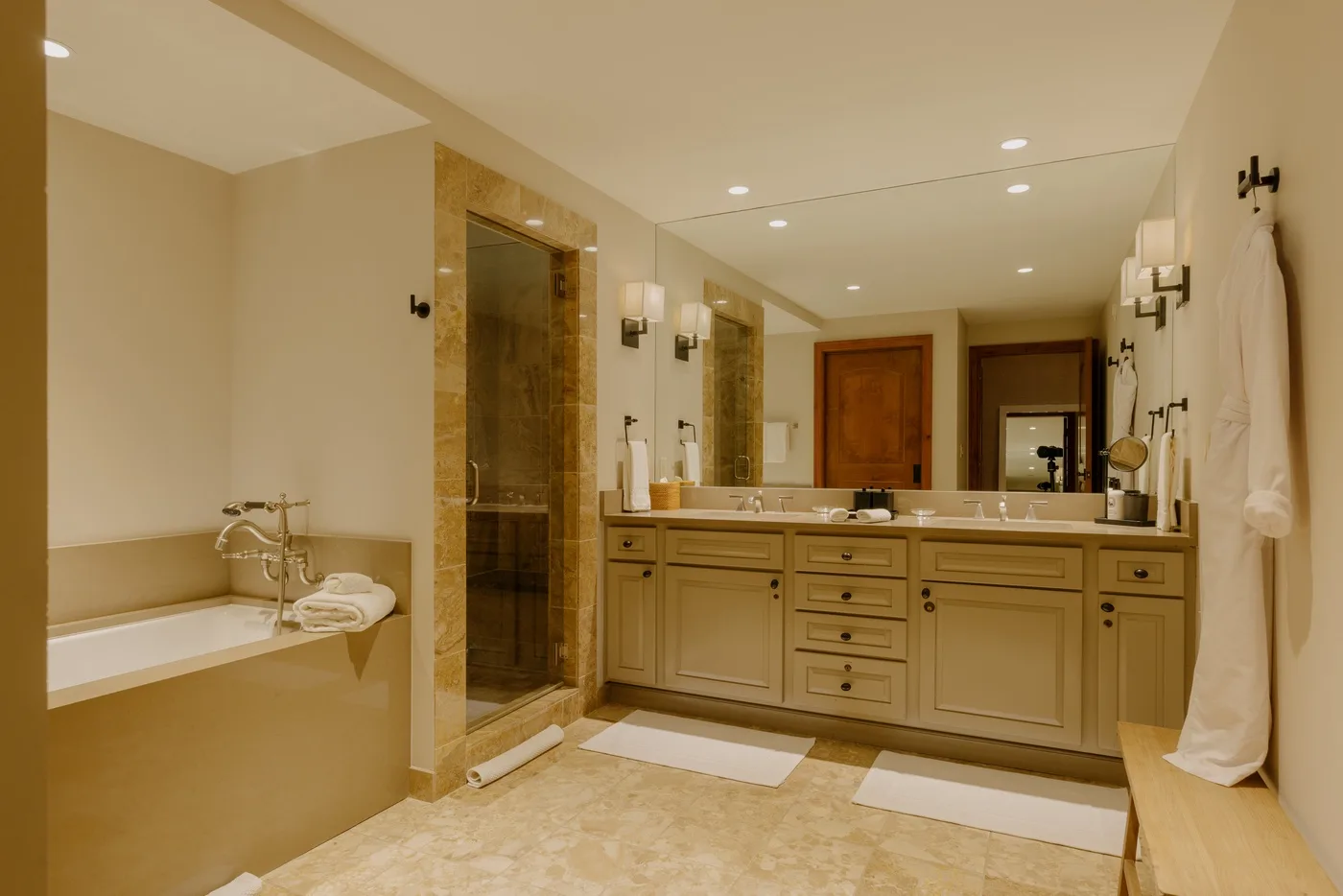 A spacious bathroom with a long vanity, wall mirrors, and a glass shower.