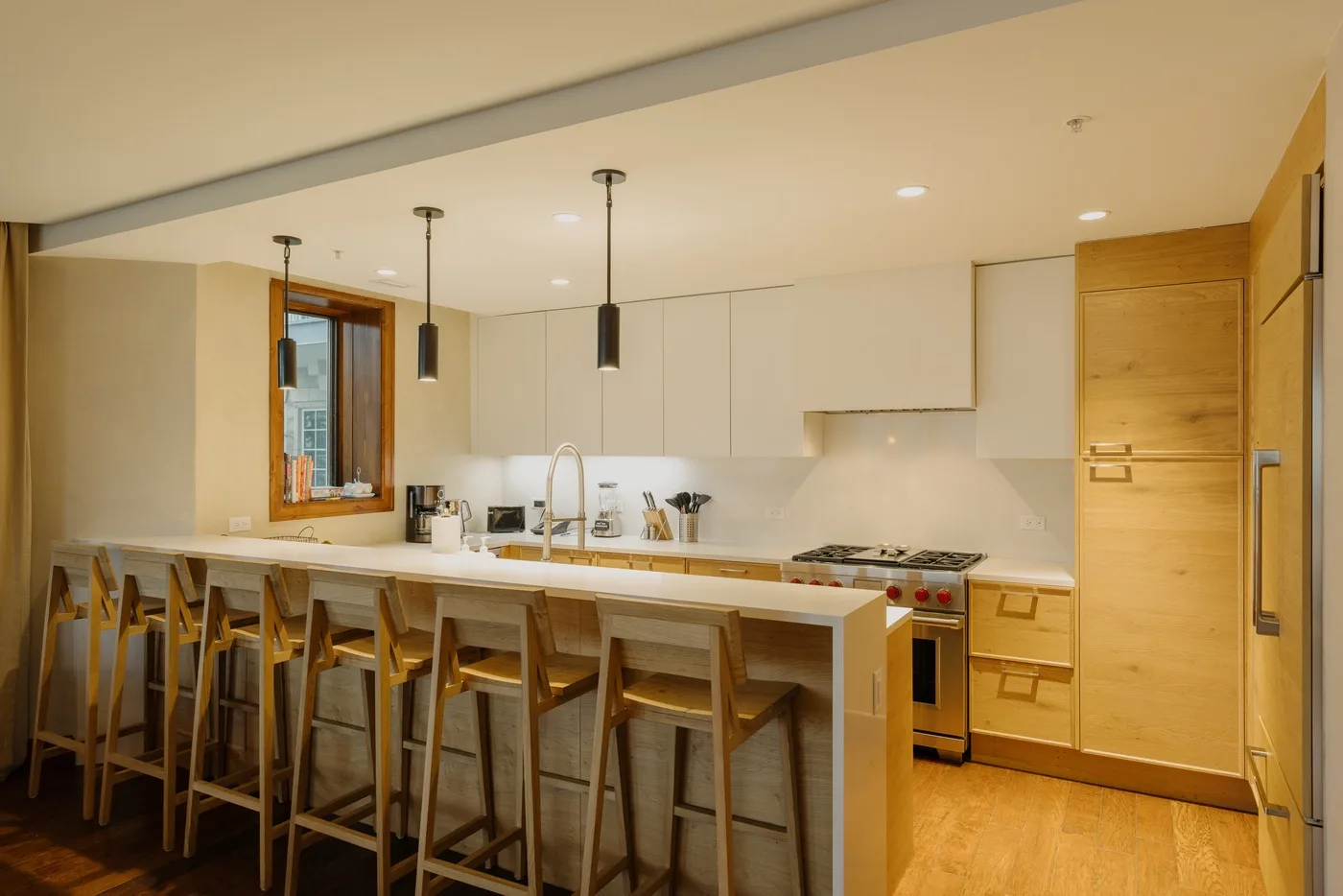 A modern kitchen with a long island and wooden bar stools.
