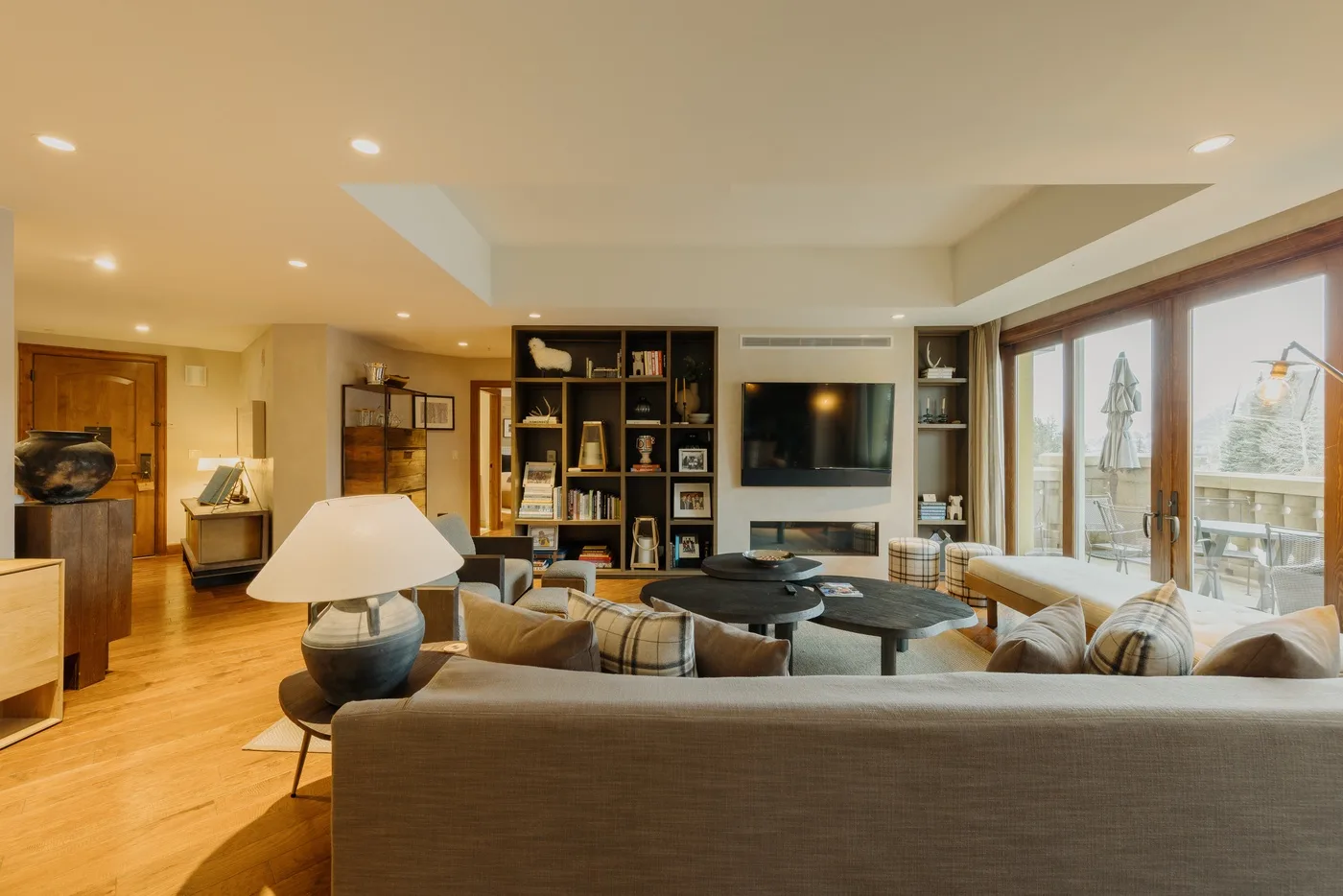 A spacious living room with seating, a television, and large windows.