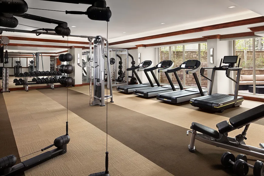 A gym with treadmills, weight machines, and a mirrored wall.