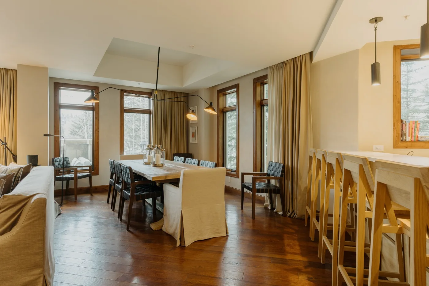 A dining area with a long table and a row of bar stools along the counter.