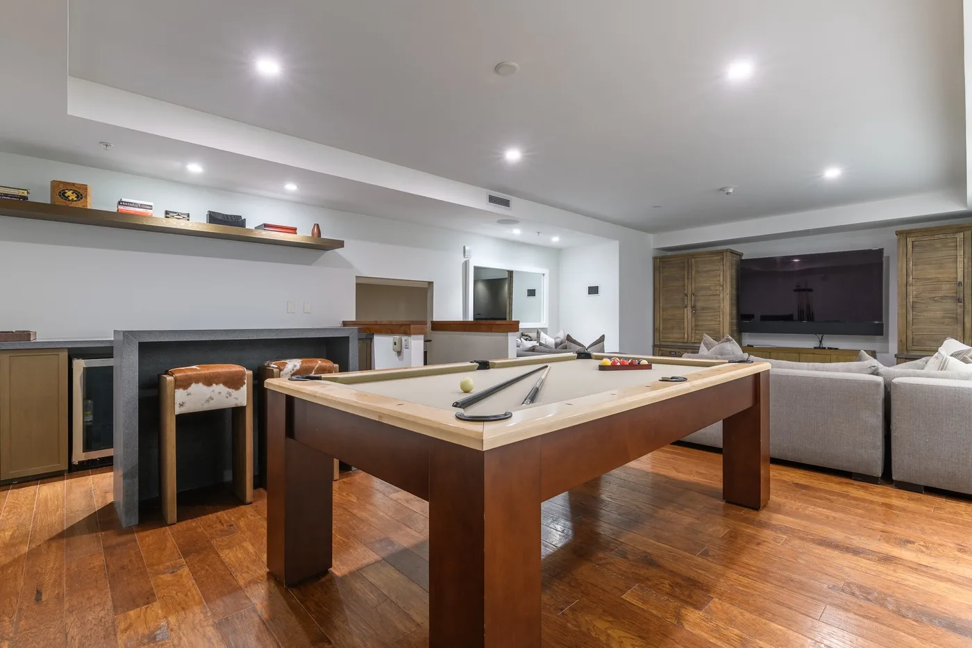 A recreation room with a pool table and seating near a wall-mounted television.