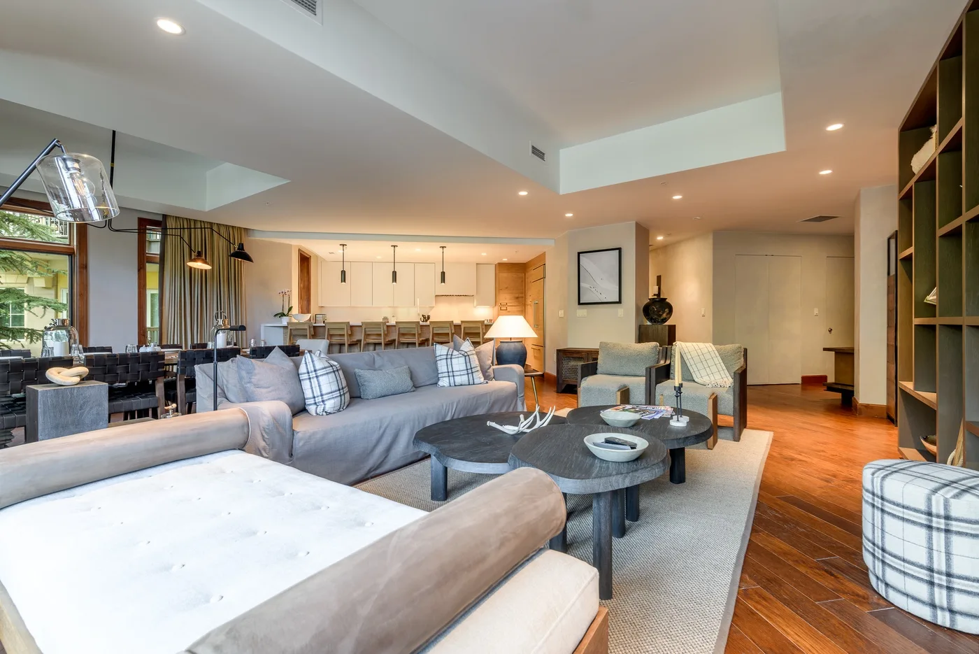 A spacious living room with seating around a coffee table and a dining area beyond.