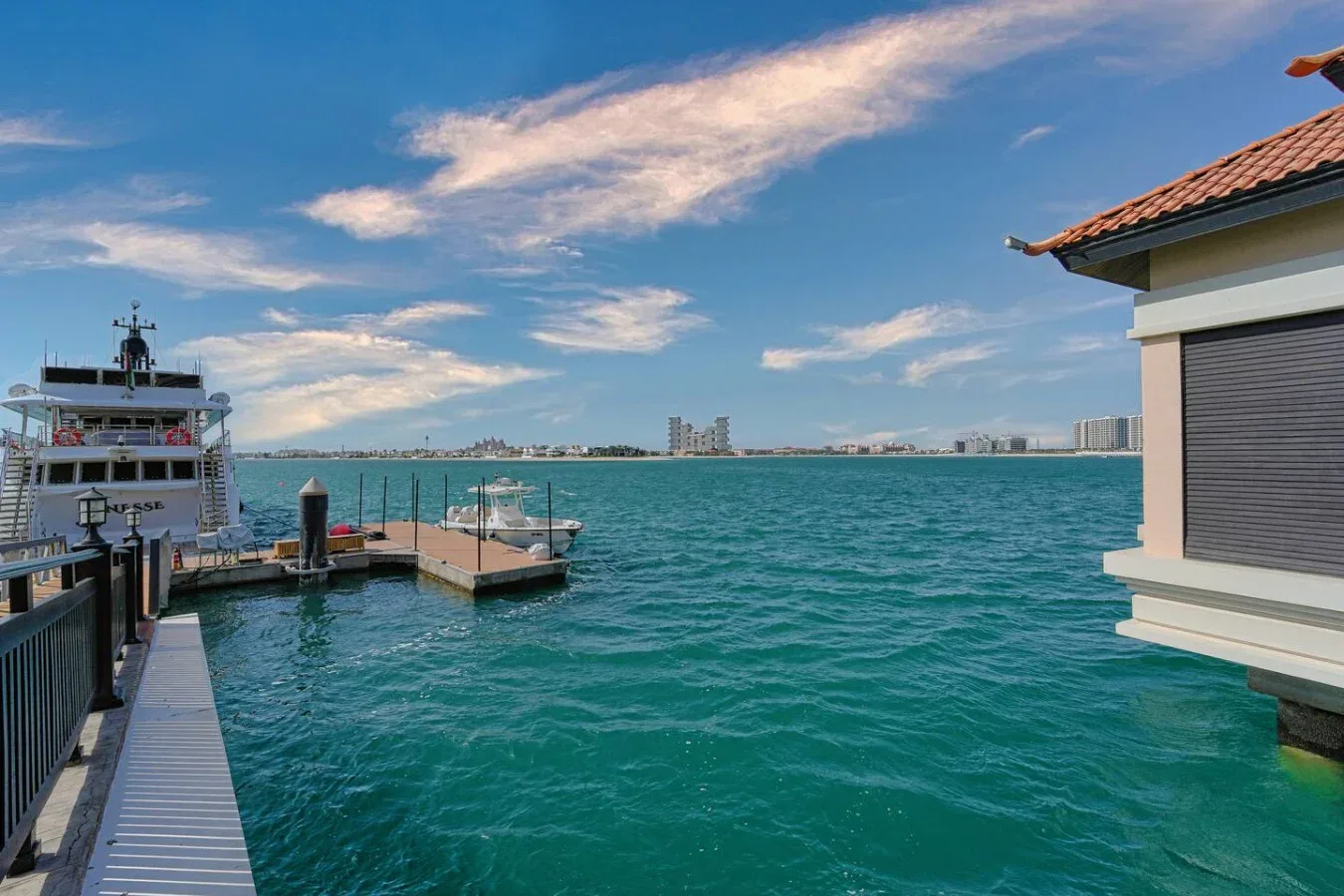 Un muelle y un barco junto a un edificio con vistas al agua azul.
