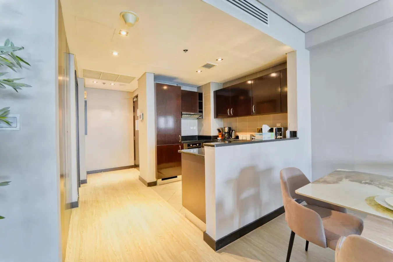 Una cocina moderna se abre a un comedor con mesa y asientos.
