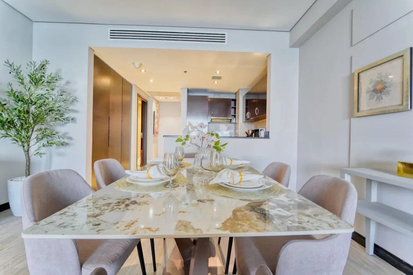 Un comedor con la mesa puesta y una cocina abierta al fondo.
