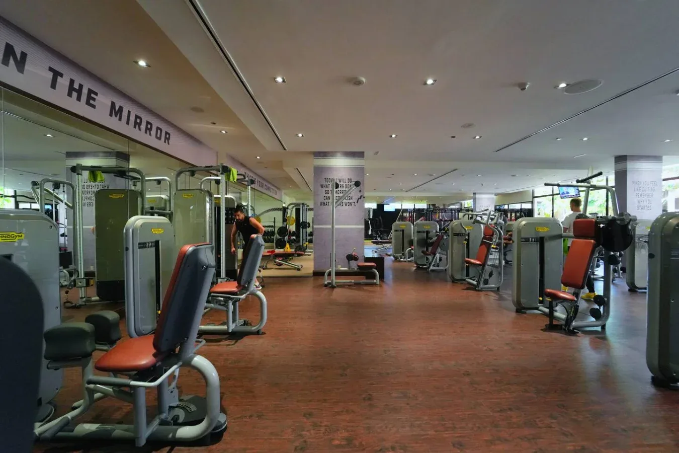 Un gimnasio con máquinas de ejercicio y una pared de espejos.