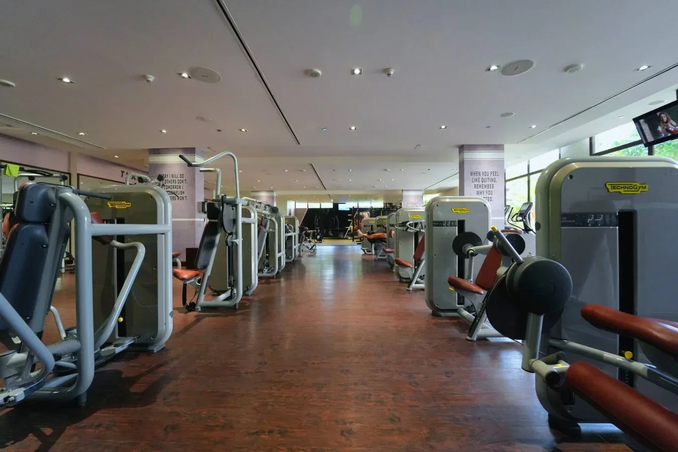 Un gimnasio con máquinas de ejercicio a lo largo de un amplio pasillo central.