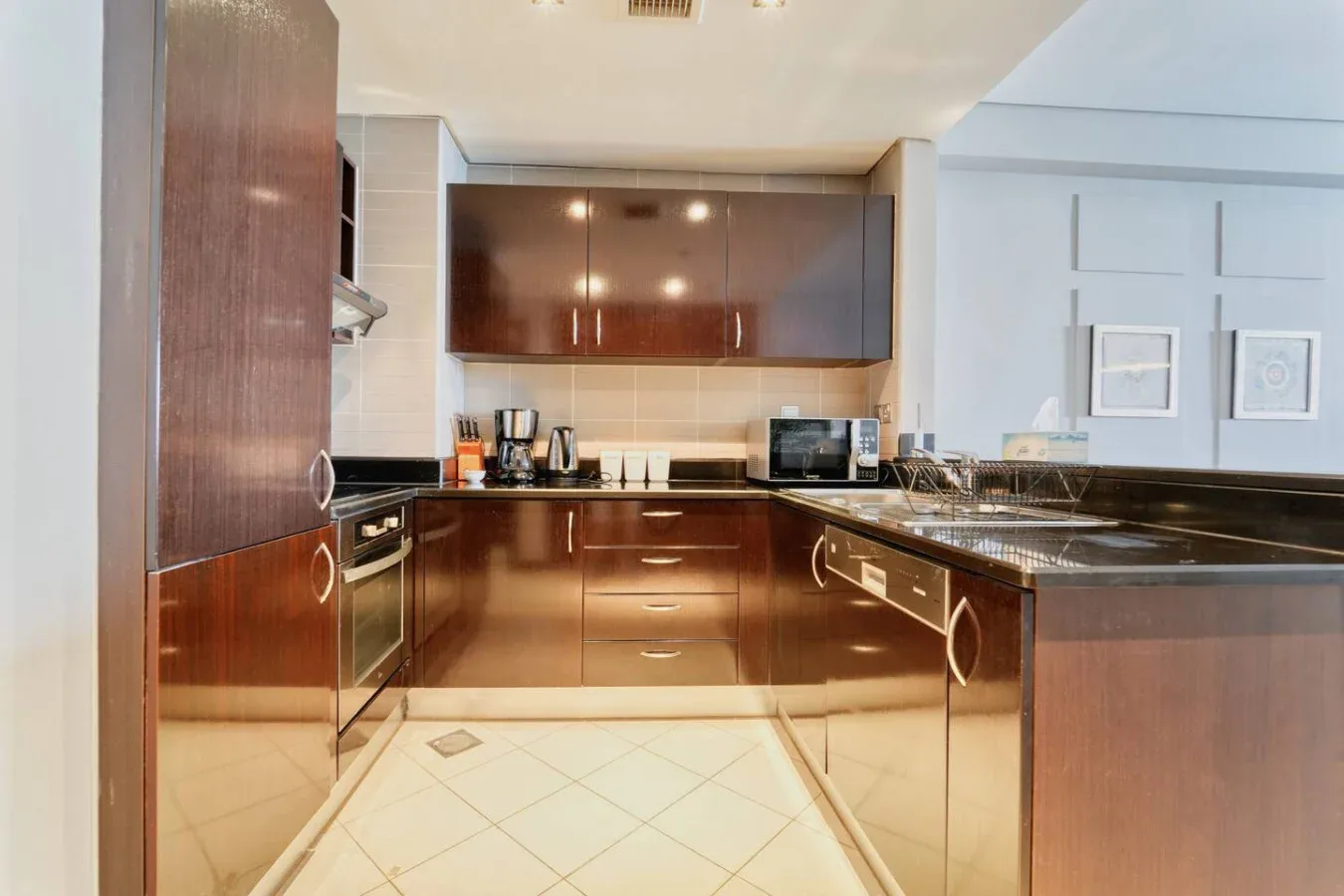 Una cocina moderna con gabinetes oscuros, encimeras claras y suelo de baldosas.