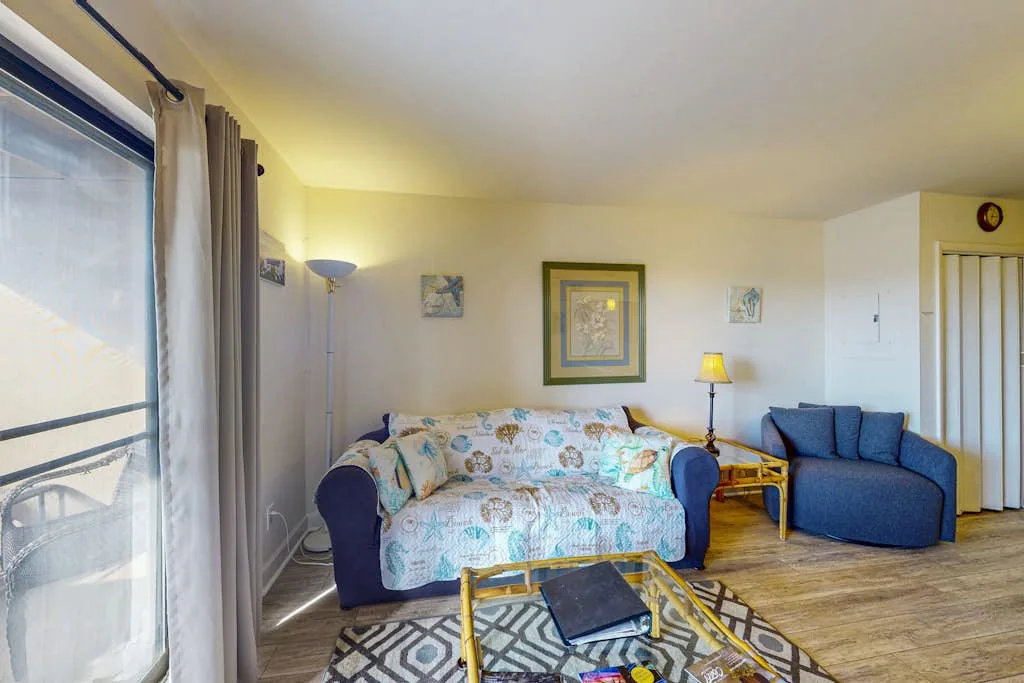 A living room with patterned seating, a blue armchair, and a coffee table.