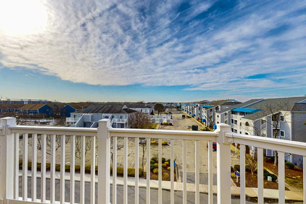A residential neighborhood is visible beyond a white railing beneath a cloudy sky.