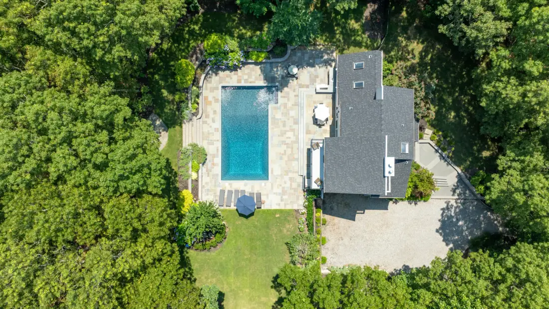 Una vista aérea muestra una casa, una piscina y árboles alrededor.