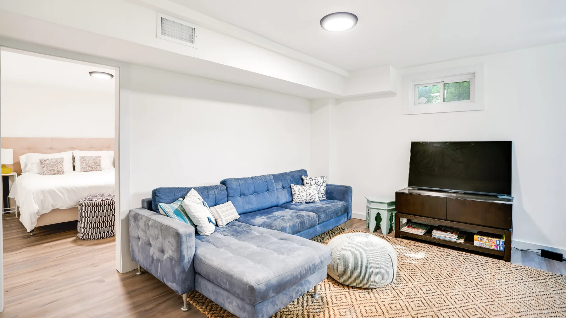 Una sala luminosa con asientos azules, un televisor y una alfombra estampada.
