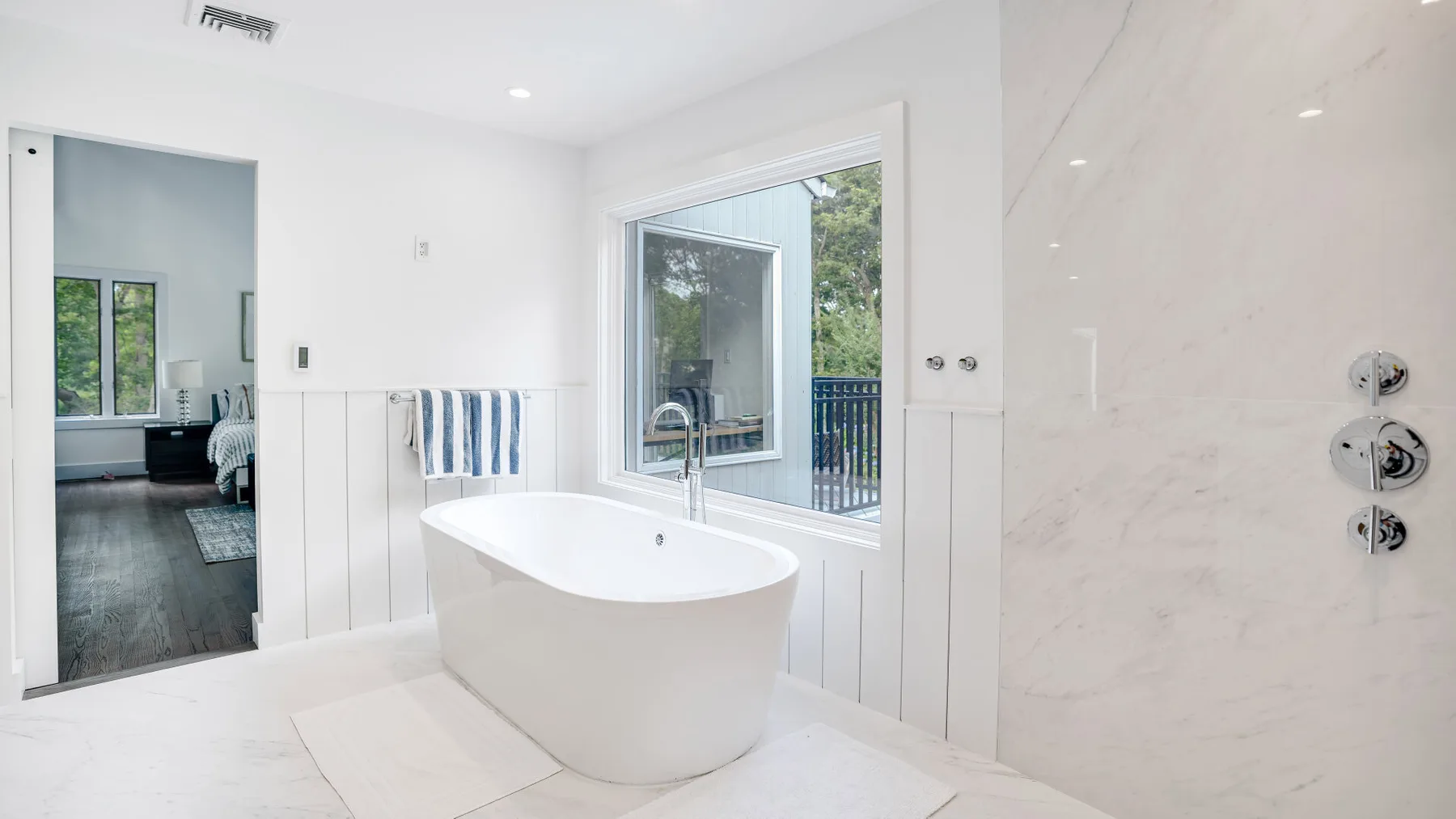 Un baño luminoso con una bañera exenta junto a una ventana amplia.