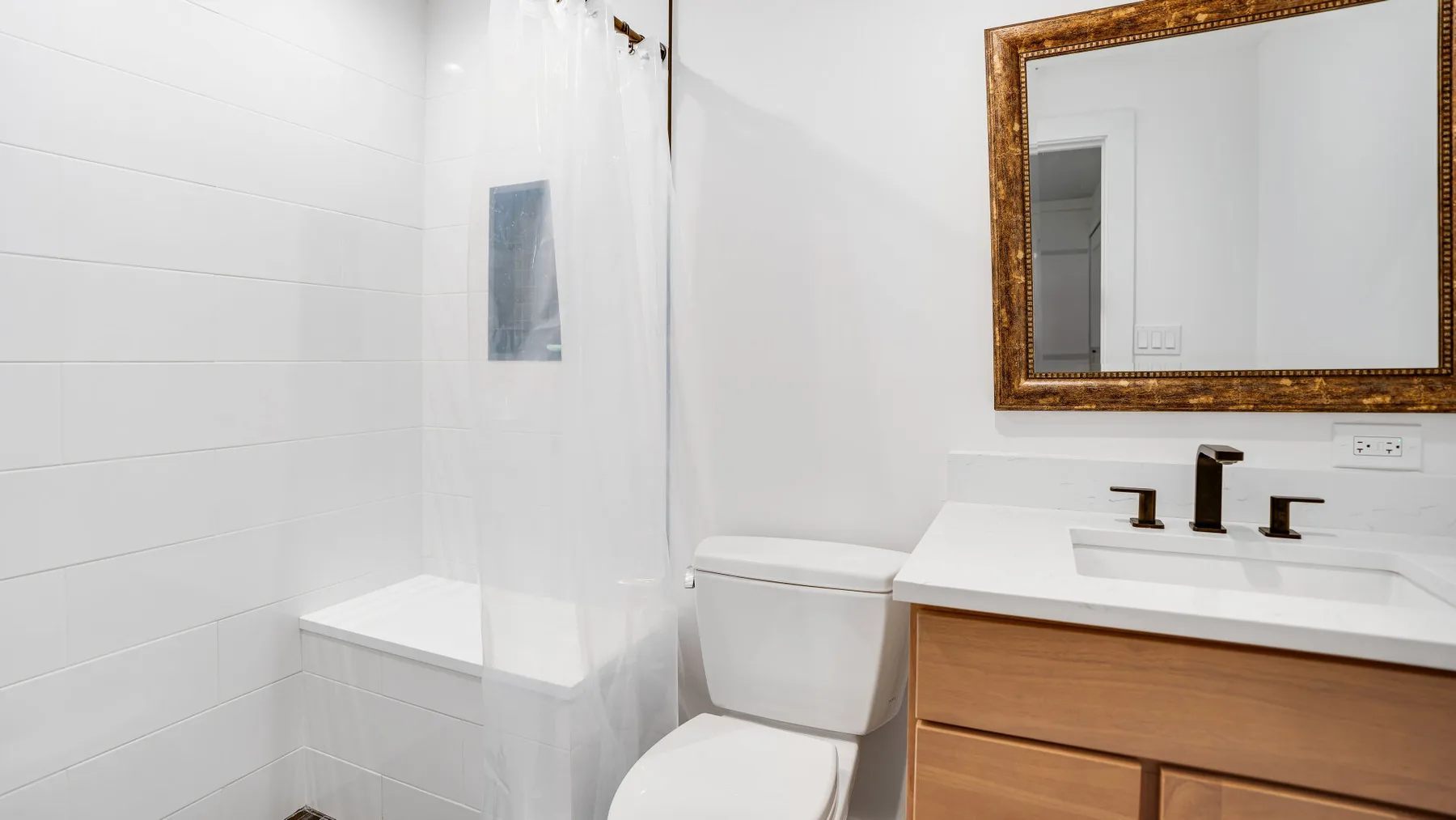 Un baño luminoso con ducha, inodoro y tocador.
