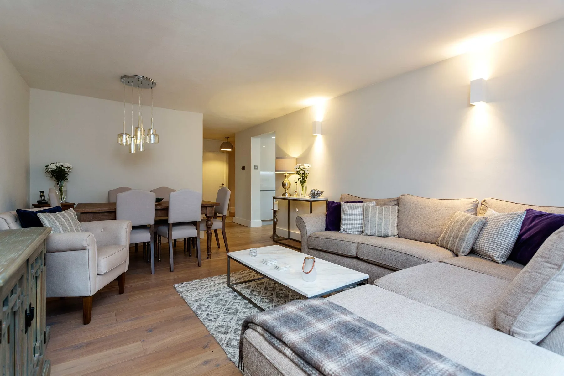 A bright living and dining area features a sectional sofa and a dining table.