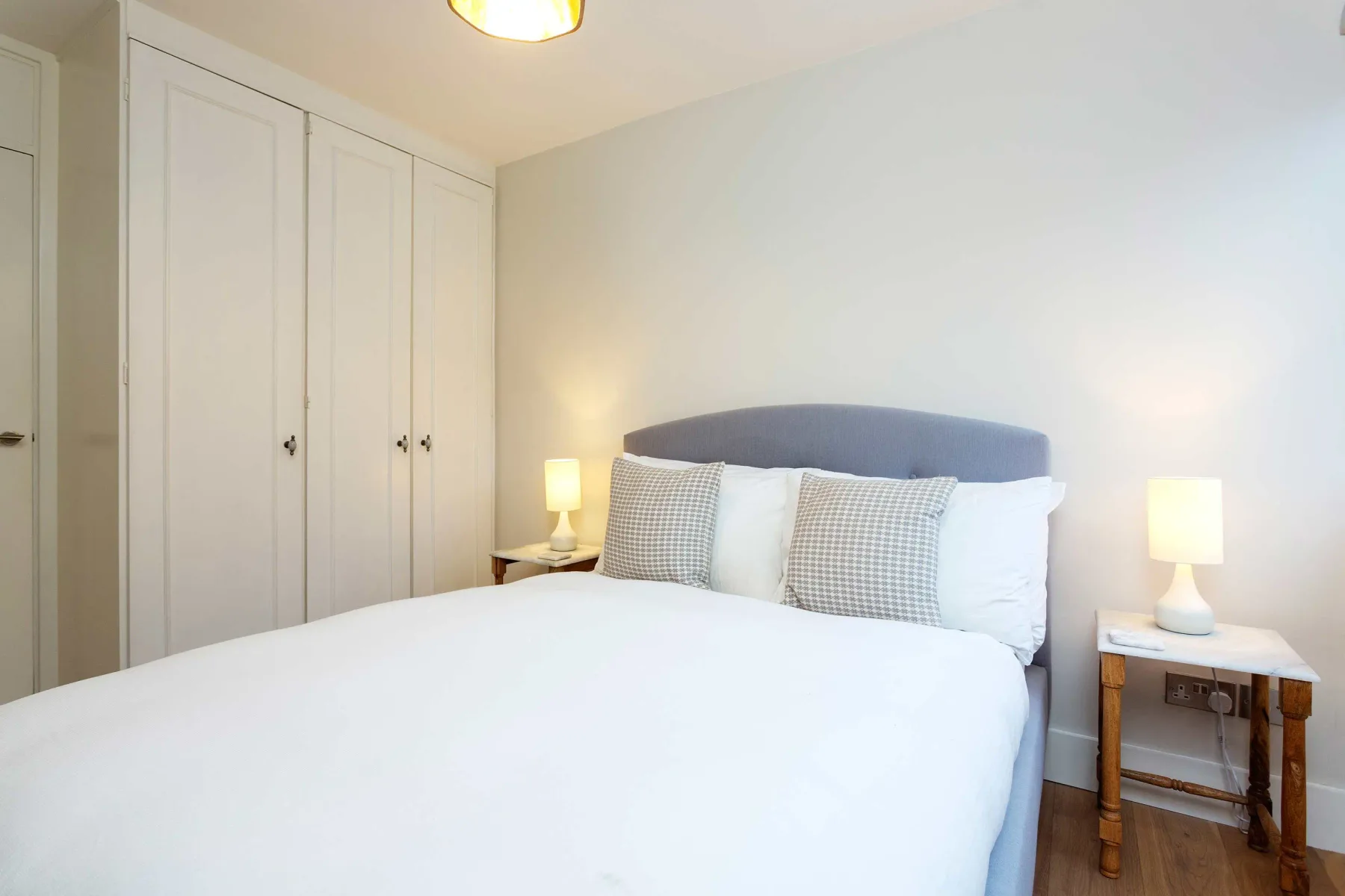 A bright bedroom with a neatly made bed and bedside tables.