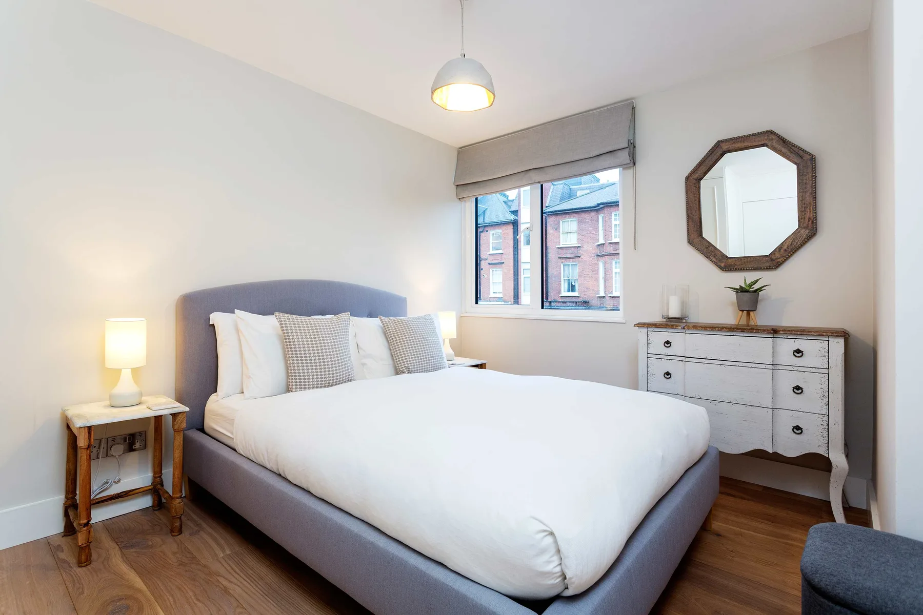A bright bedroom with a neatly made bed and a window.
