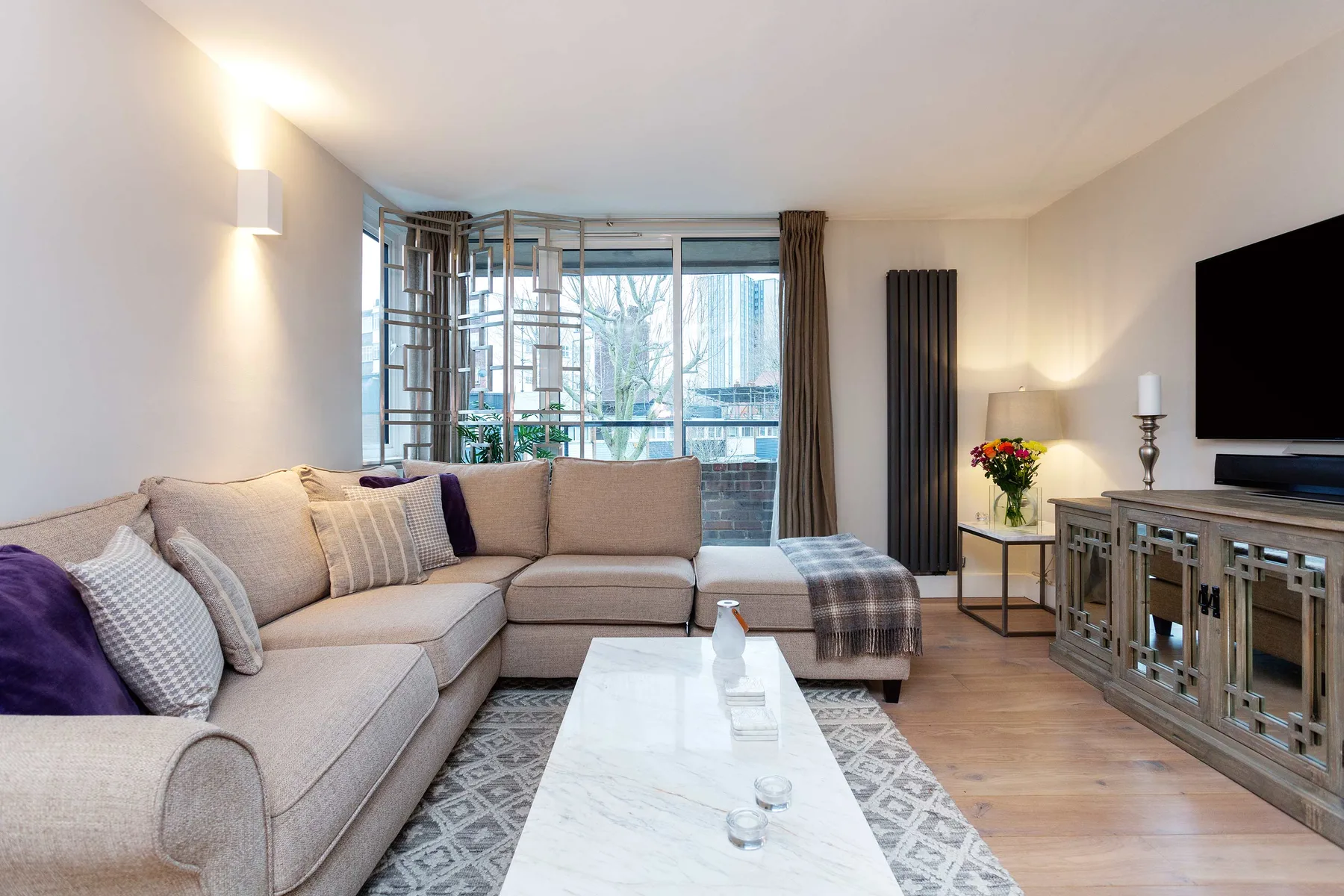 A bright living room with a sectional sofa, coffee table, and large windows.