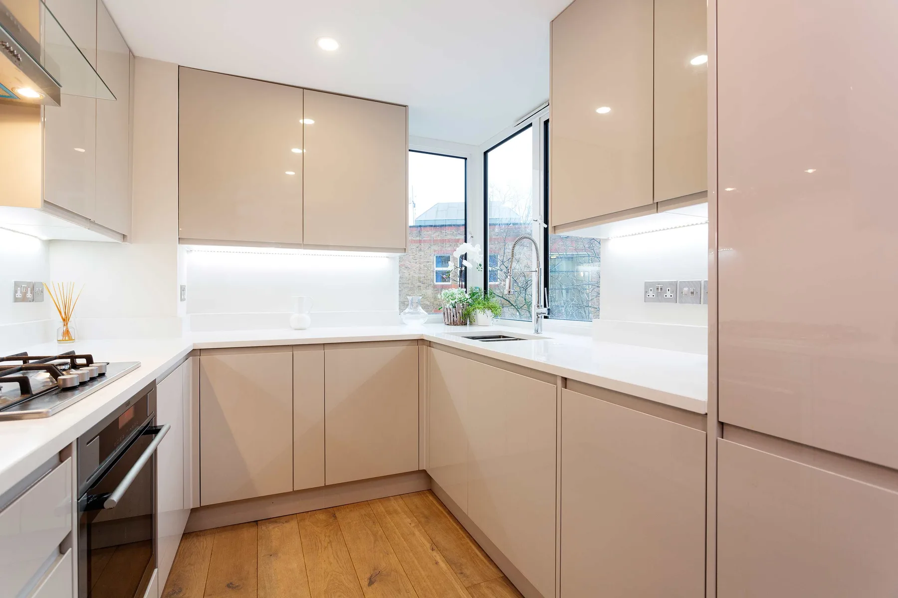 A modern kitchen with pale cabinetry, light countertops, and a window by the sink.