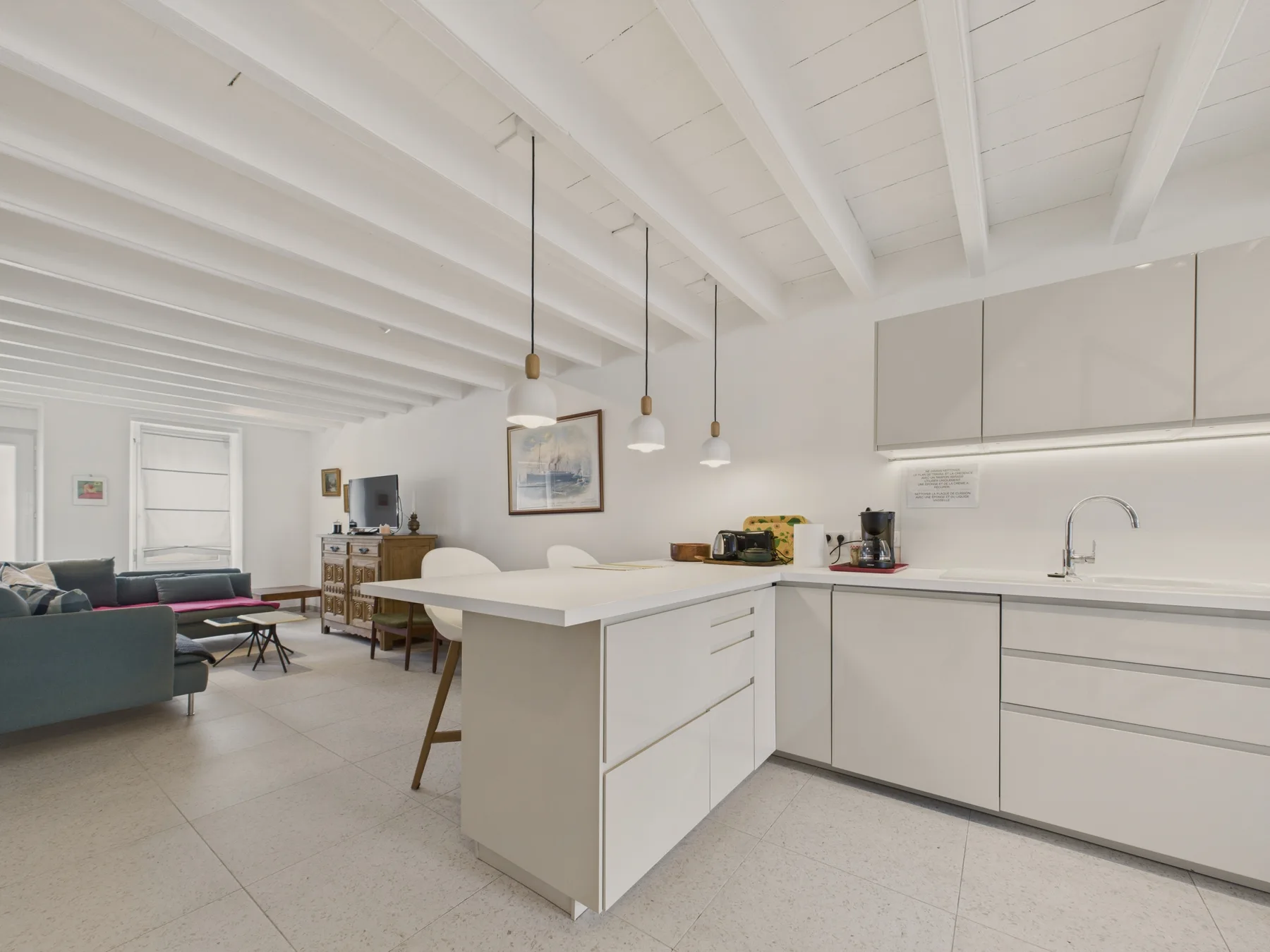 A bright open-plan kitchen and living area with a central island and seating.