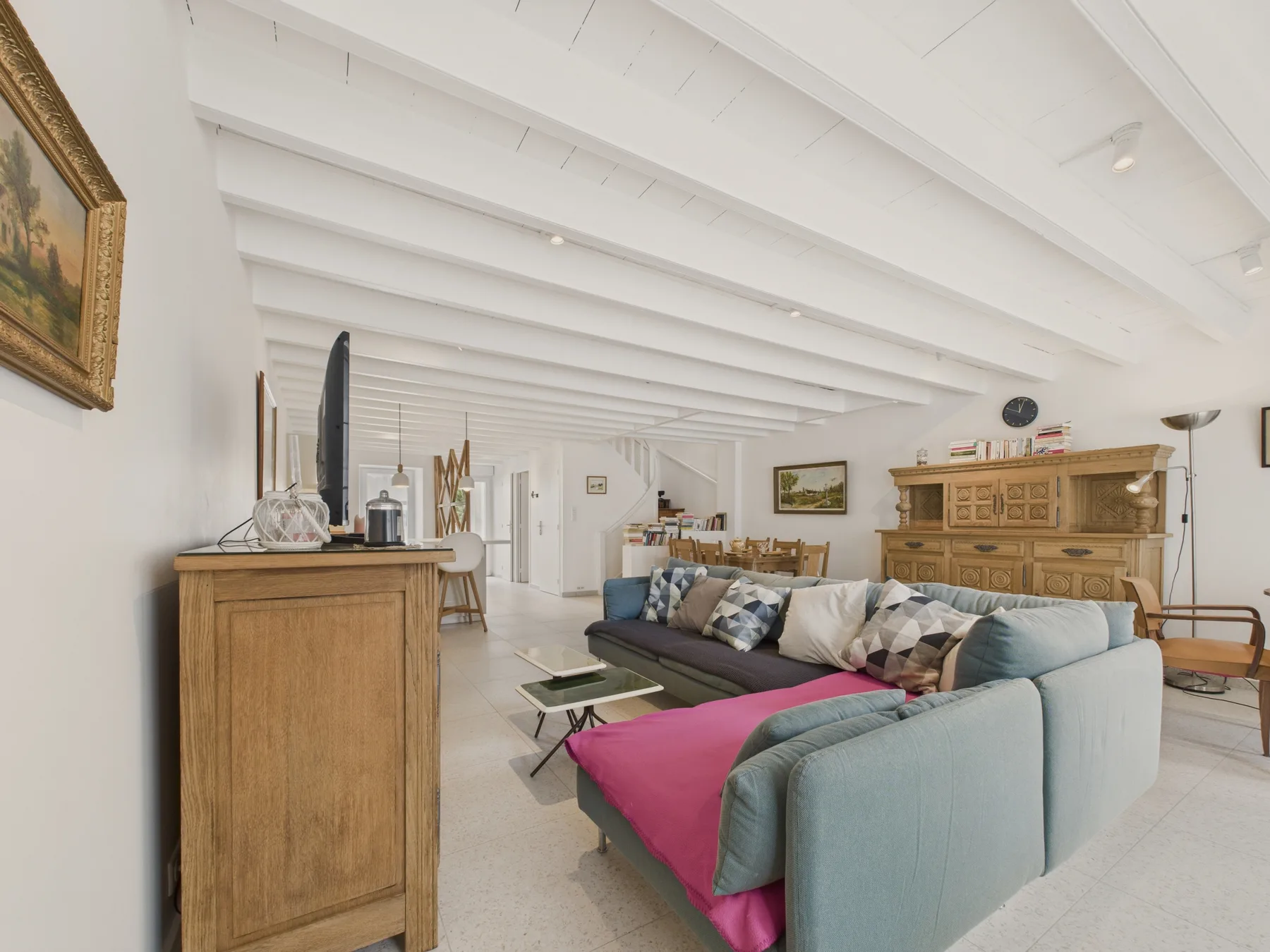 Living room with seating, a wooden cabinet, and exposed ceiling beams.