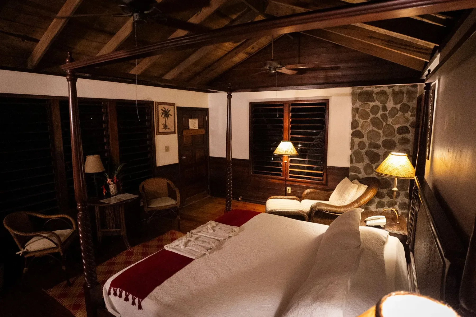 Un dormitorio con una cama de cuatro postes y un ventilador de techo.