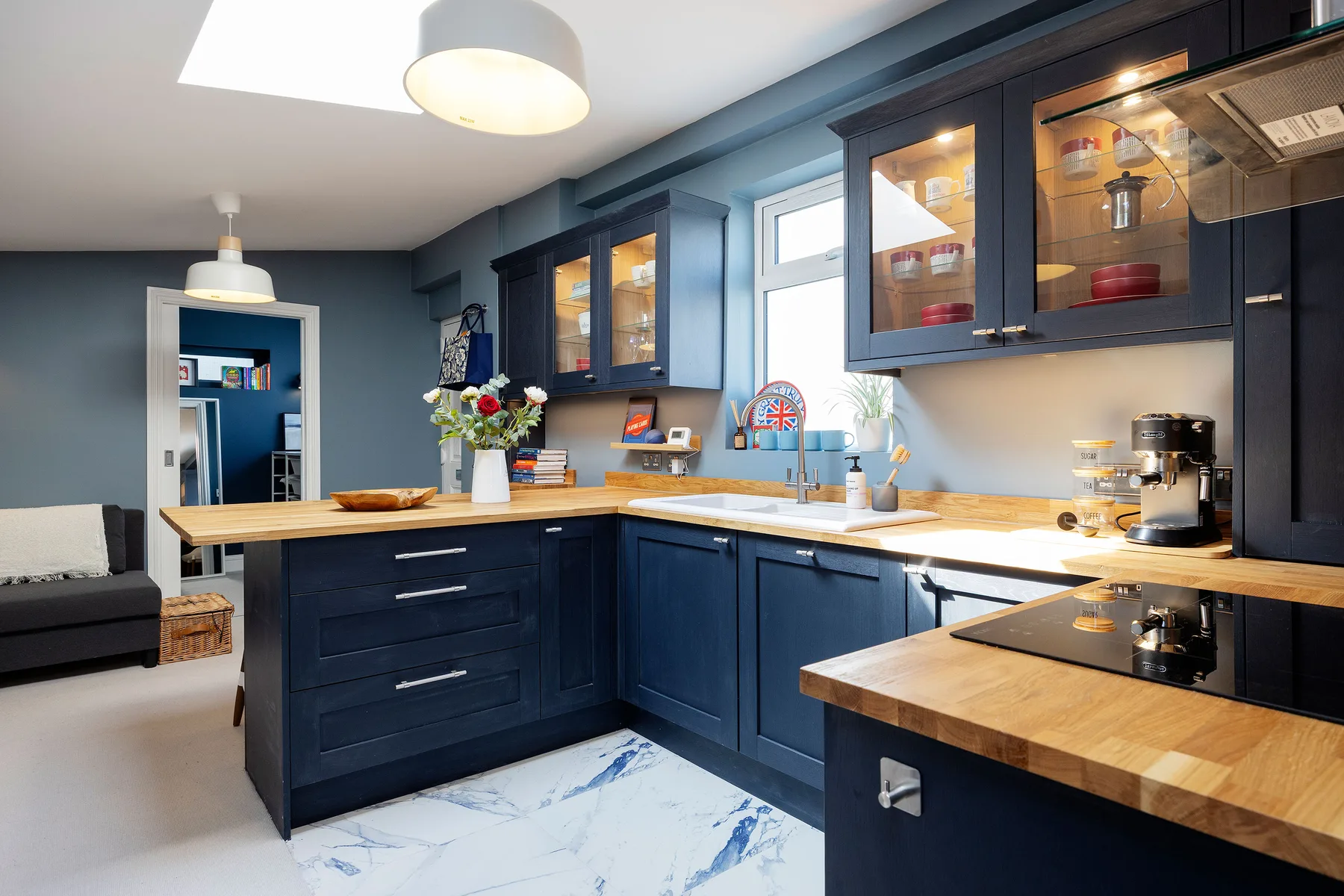 A dark blue kitchen with wooden countertops, glass-front cabinets, and a central island.
