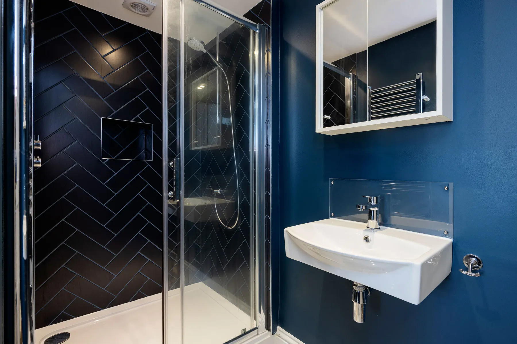A modern bathroom with a glass shower and wall-mounted sink.