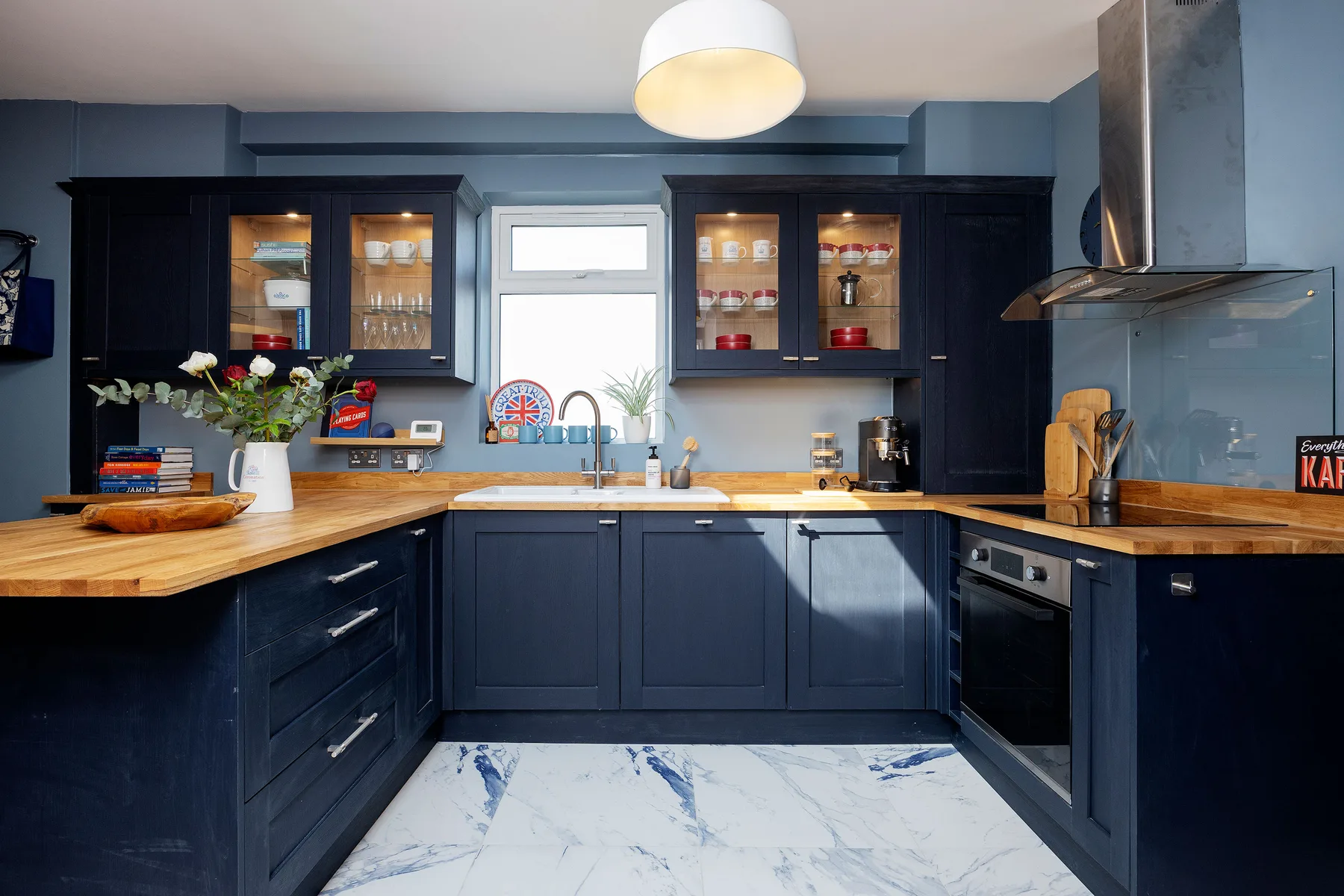 A dark blue kitchen with wooden countertops and a bright patterned floor.