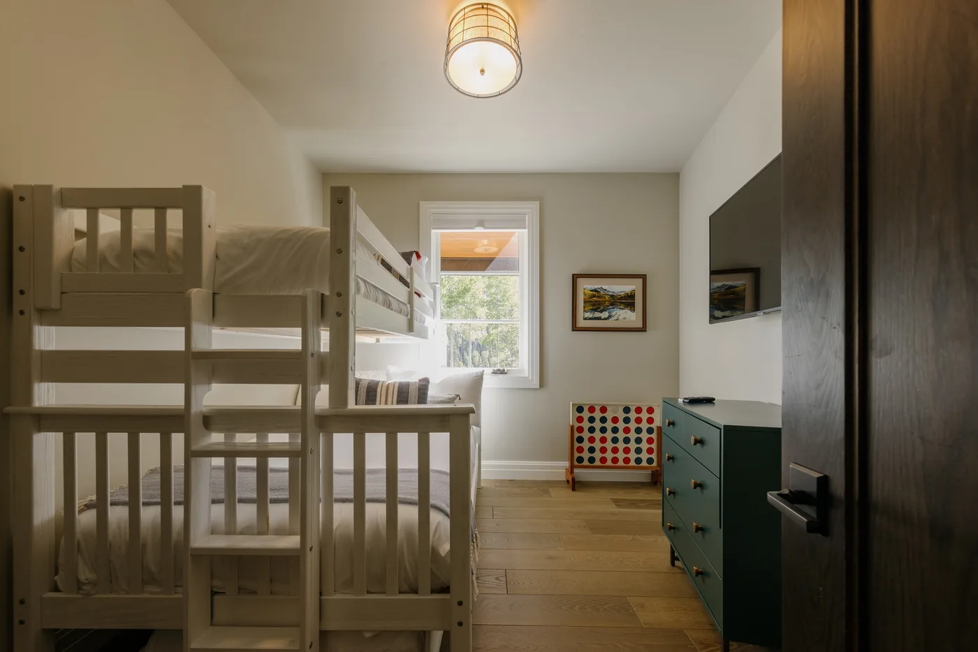 A bedroom with bunk beds, a window, and a dresser.