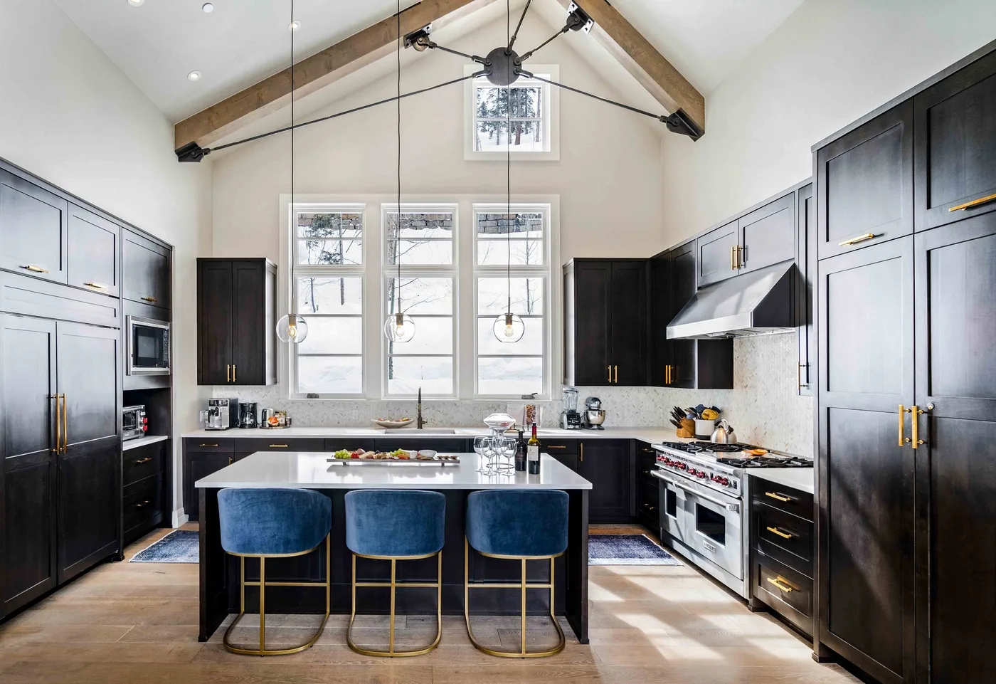 A spacious kitchen with dark cabinetry, a central island, and a vaulted ceiling.