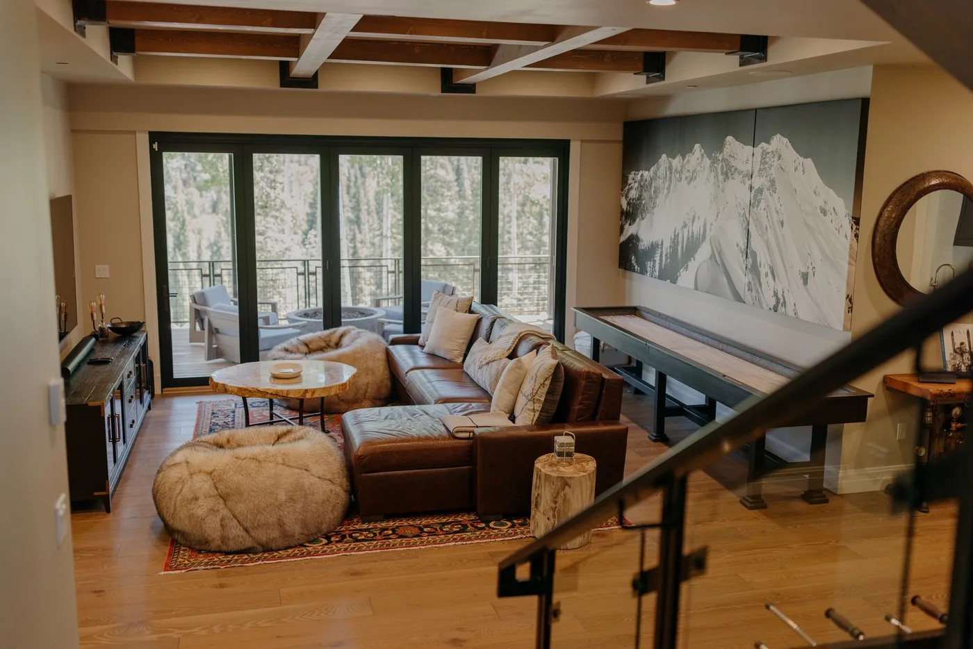 A warm living room with seating arranged around a low table beside large windows.
