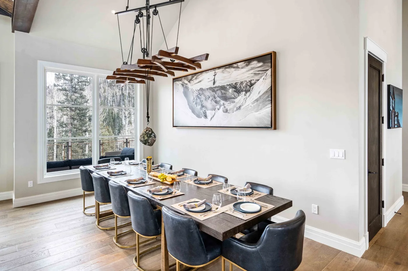 A dining area with a long table set with dishes beneath a wooden chandelier.