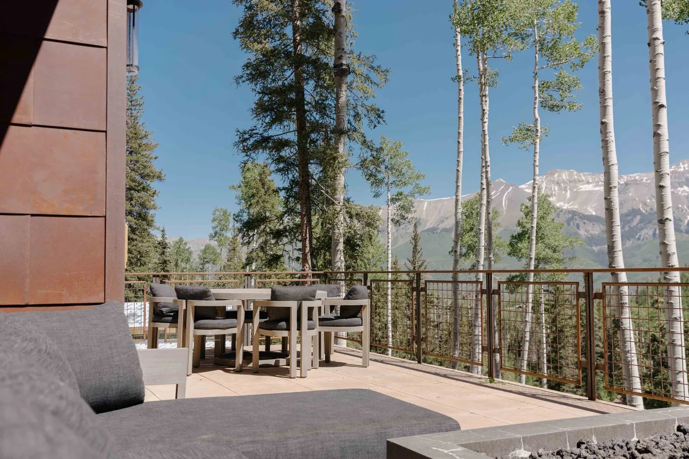 An outdoor dining area with seating overlooks trees and distant mountains.