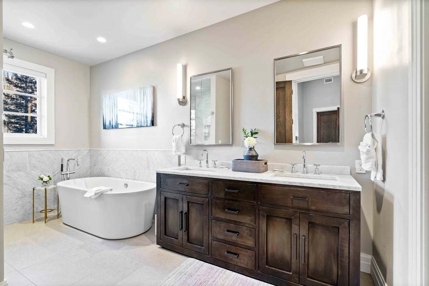 A bright bathroom has a double-sink vanity and a freestanding bathtub.