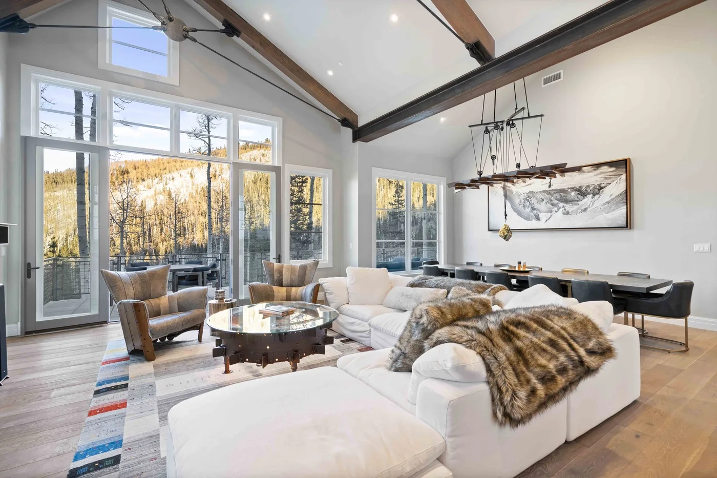 A bright open-plan living and dining room with large windows and comfortable seating.
