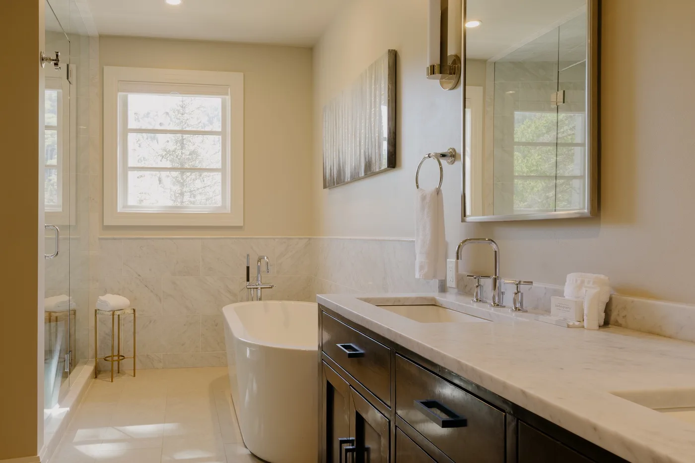 A bright bathroom with a bathtub, vanity, and large mirror.