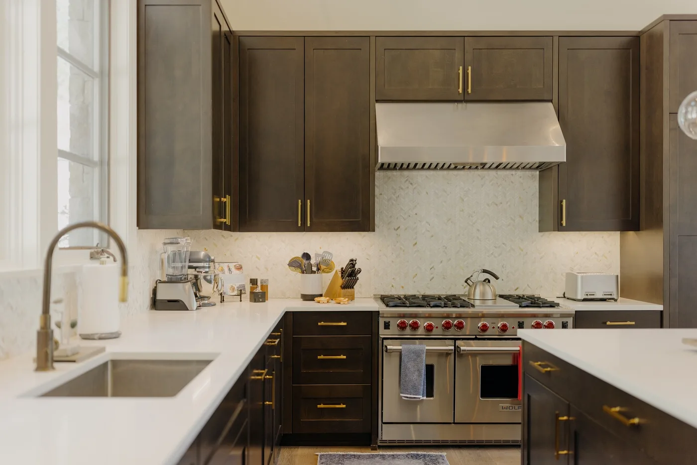 A kitchen with dark cabinets, white countertops, and a stainless steel range.