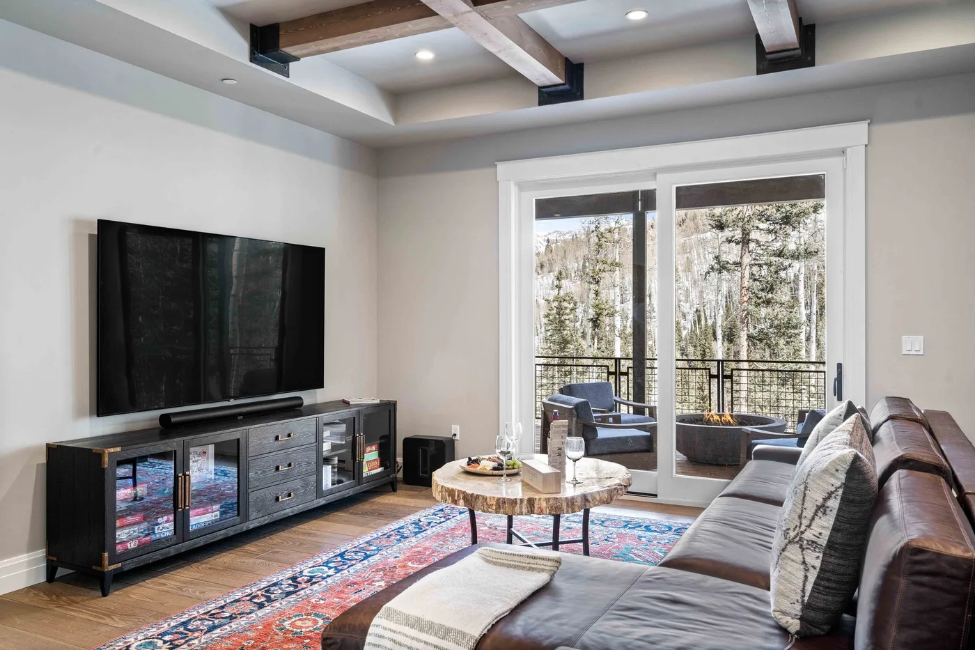 A living room with seating, a television, and glass doors opening to a balcony.
