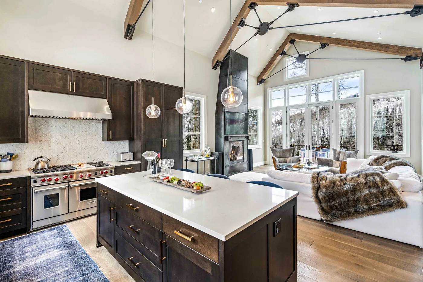 An open kitchen and living area with a large island and seating by the windows.