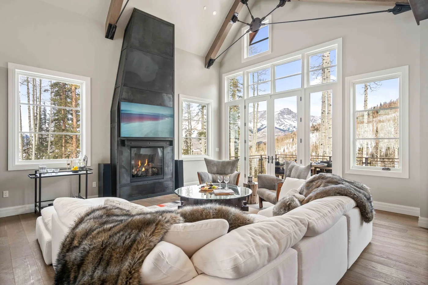 A bright living room with large windows, a fireplace, and seating.