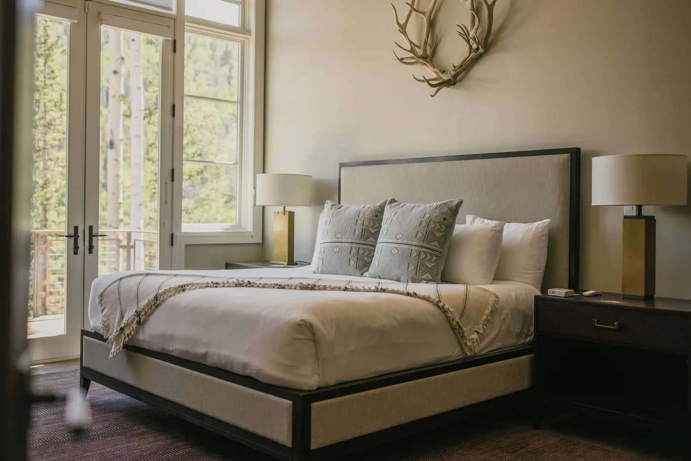 A bedroom with a neatly made bed and tall windows.