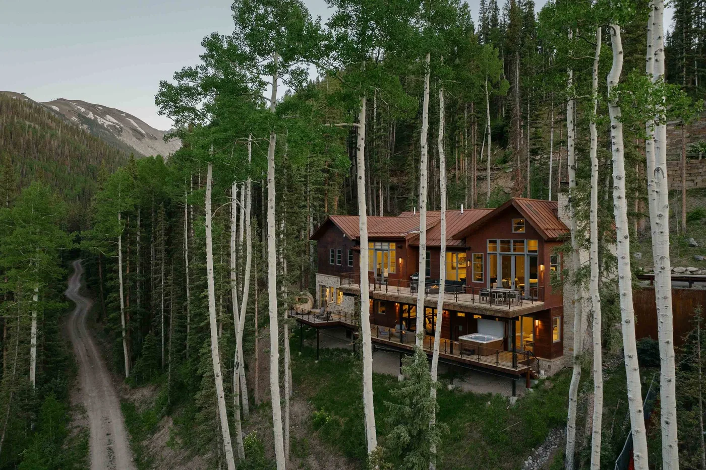 A wooden cabin sits among trees on a wooded hillside.