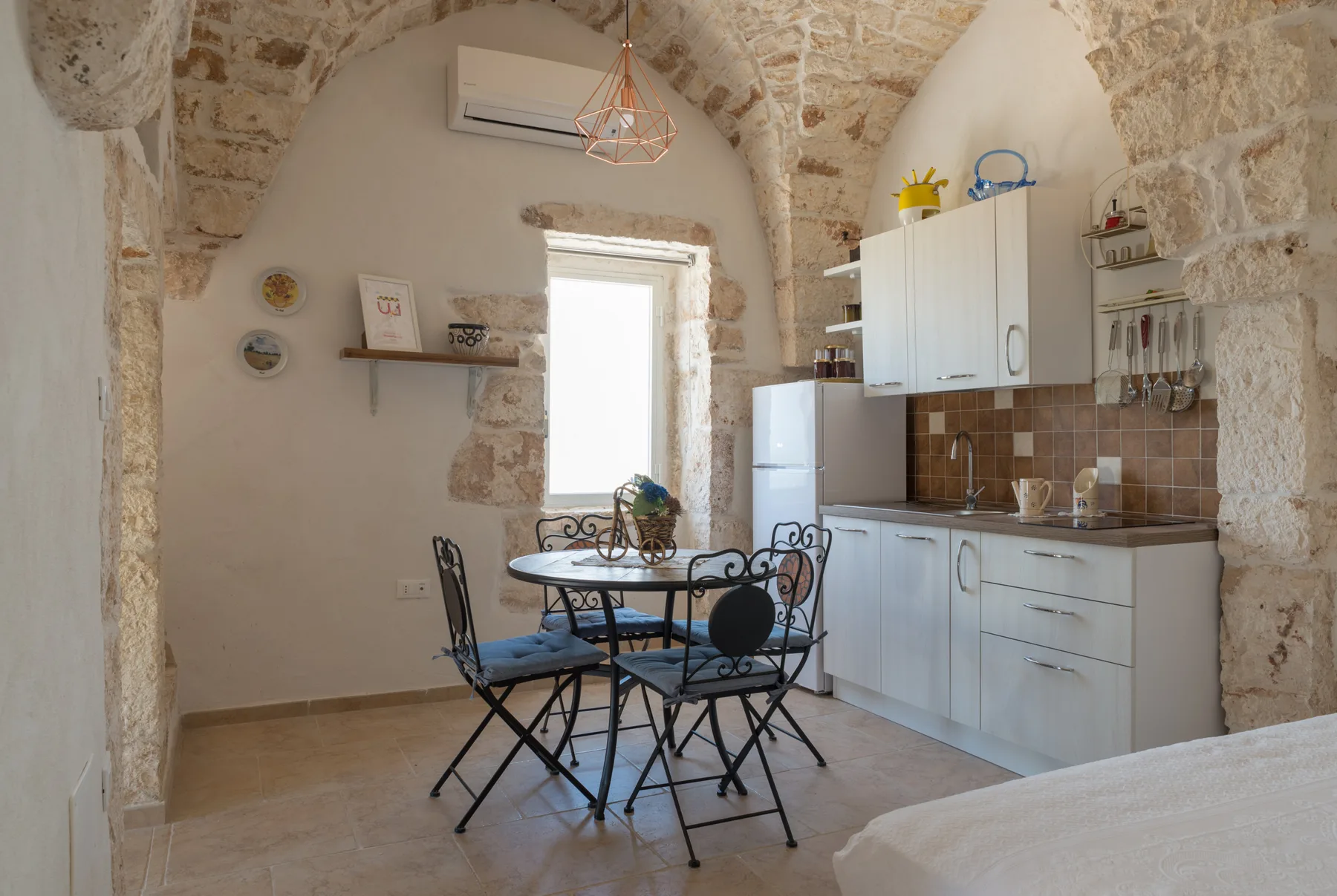 Una cocina y comedor con paredes de piedra, mesa y asientos.