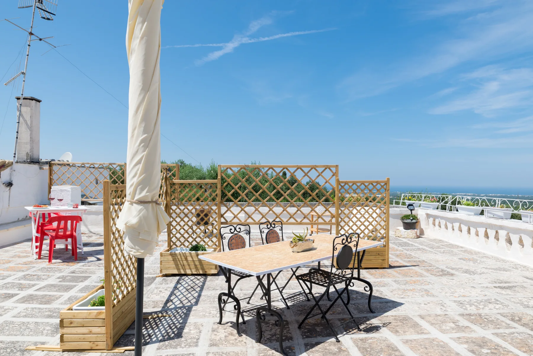 Una terraza soleada en la azotea con mesa, sillas y celosías.
